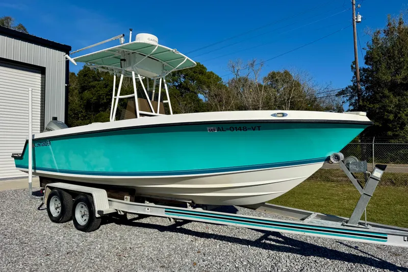 The Image of 2000 Contender 23 Open boat on trailer, turquoise hull, parked outdoors. - 1