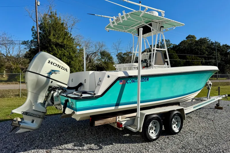 Slide: The Image of 2000 Contender 23 Open boat with Honda outboard motor on trailer, parked outdoors. - 3