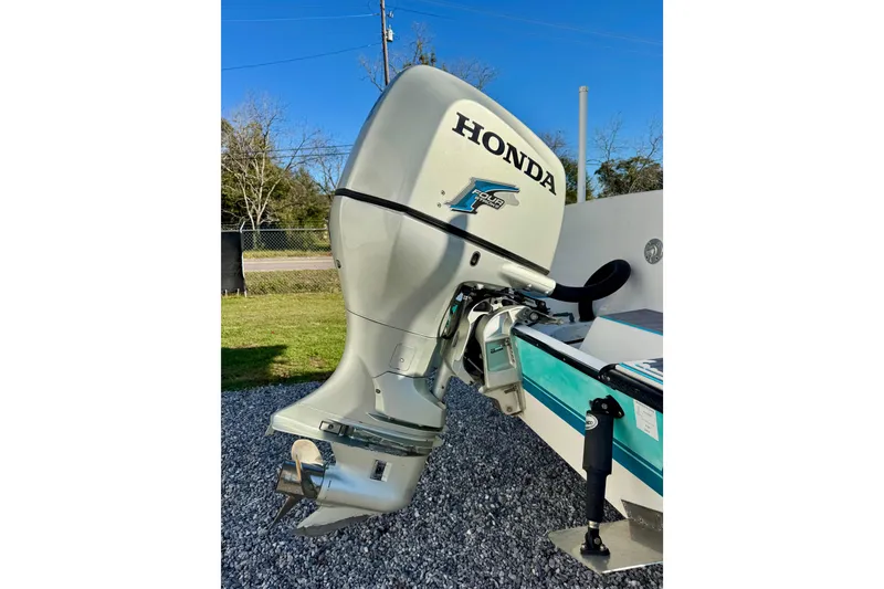 Slide: The Image of Honda outboard motor on 2000 Contender 23 Open boat, parked on gravel. - 4