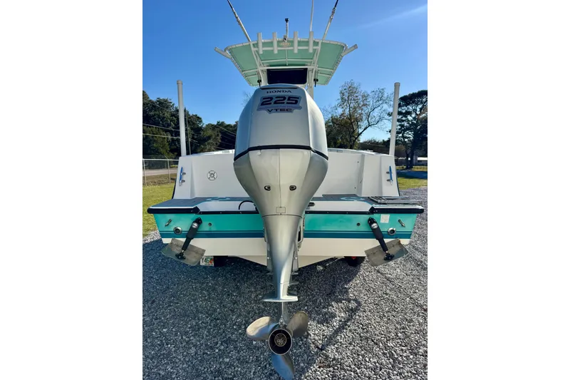 Slide: The Image of 2000 Contender 23 Open boat with Honda 225 VTEC outboard motor, parked on gravel. - 5