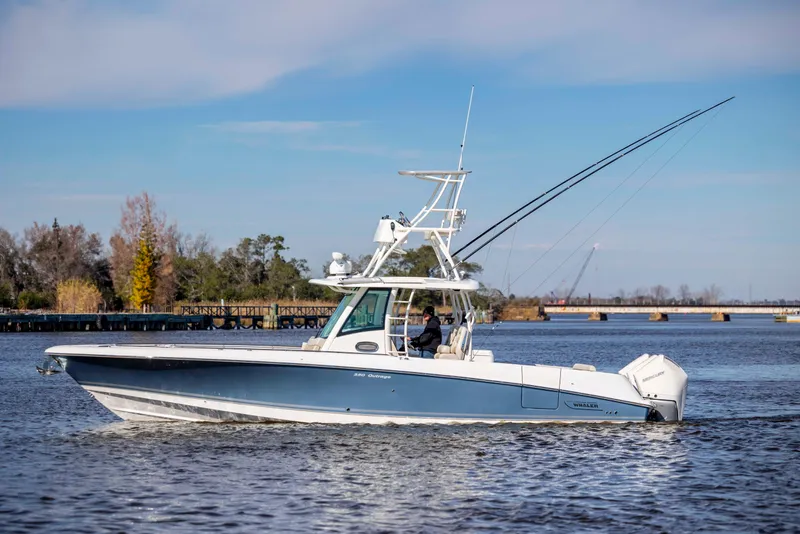 Slide: The Image of 2019 Boston Whaler 350 Outrage boat cruising on a calm river with scenic background. - 11