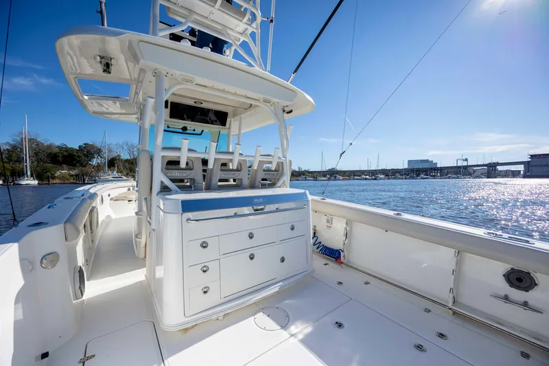 Slide: The Image of 2019 Boston Whaler 350 Outrage boat interior with seating and storage, docked by a sunny waterfront. - 16