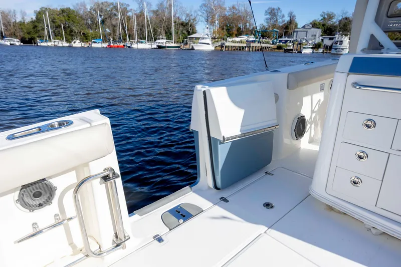 Slide: The Image of 2019 Boston Whaler 350 Outrage boat interior with open water view and docked sailboats. - 18