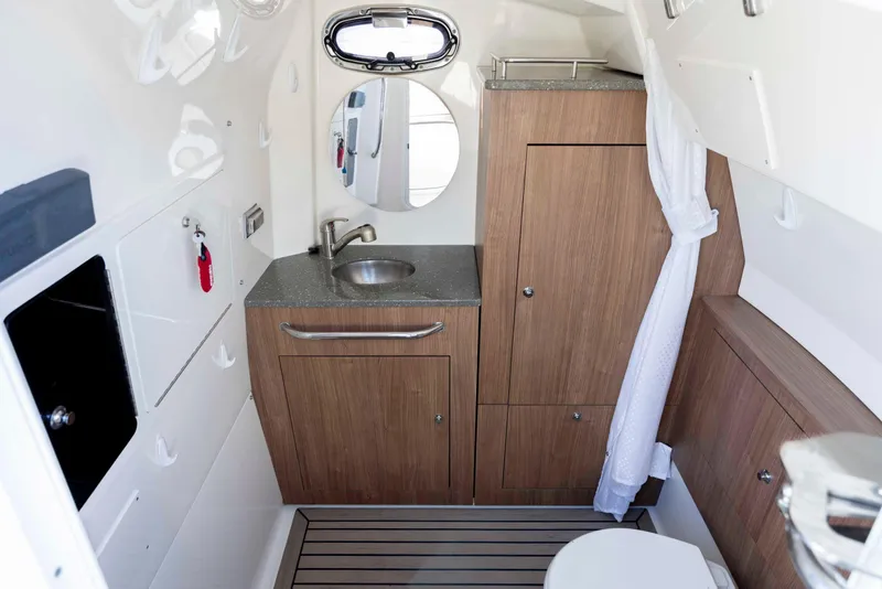 Slide: The Image of 2019 Boston Whaler 350 Outrage cabin interior with sink, mirror, and wooden cabinetry. - 35