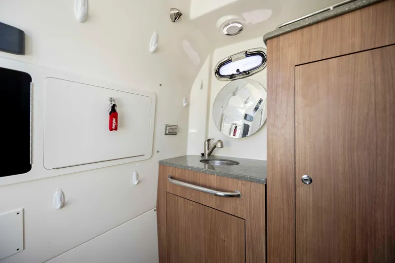 Slide: The Image of 2019 Boston Whaler 350 Outrage cabin interior with sink, mirror, and storage. - 36
