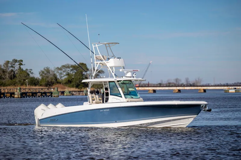 Slide: The Image of 2019 Boston Whaler 350 Outrage boat cruising on a calm river under a clear blue sky. - 7