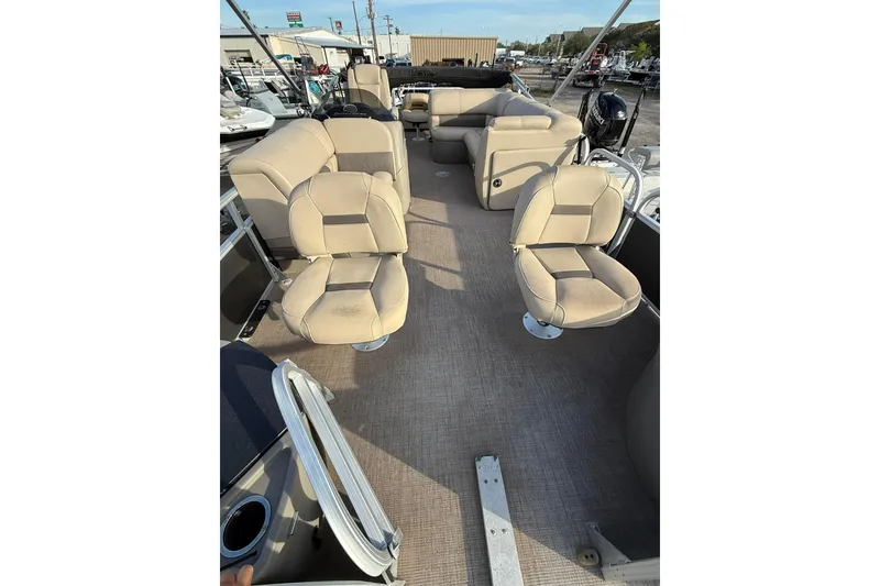 Slide: The Image of 2023 Sun Tracker Fishin' Barge 22 DLX interior with beige seating and steering console. - 4