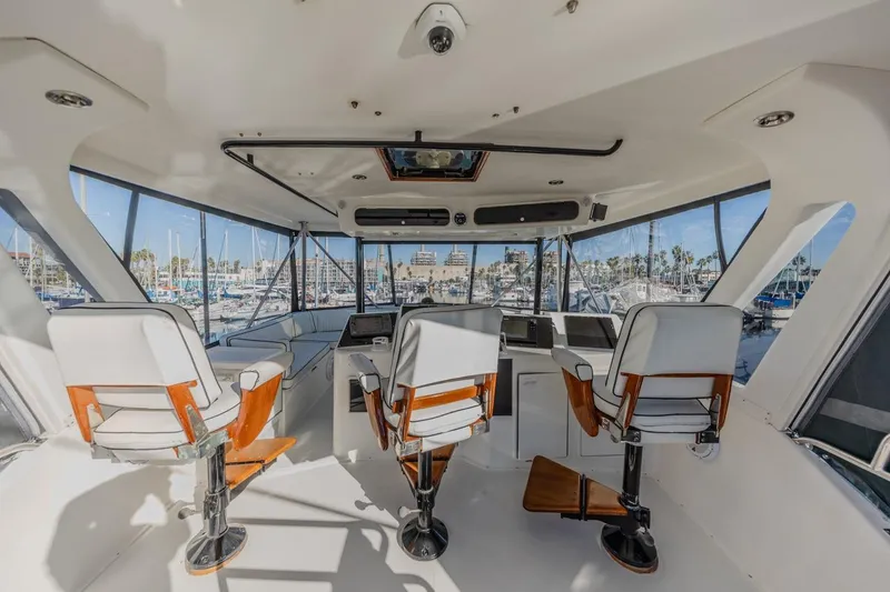 Slide: The Image of Interior view of 1993 Ocean 65 Custom yacht helm with three chairs and marina backdrop. - 11