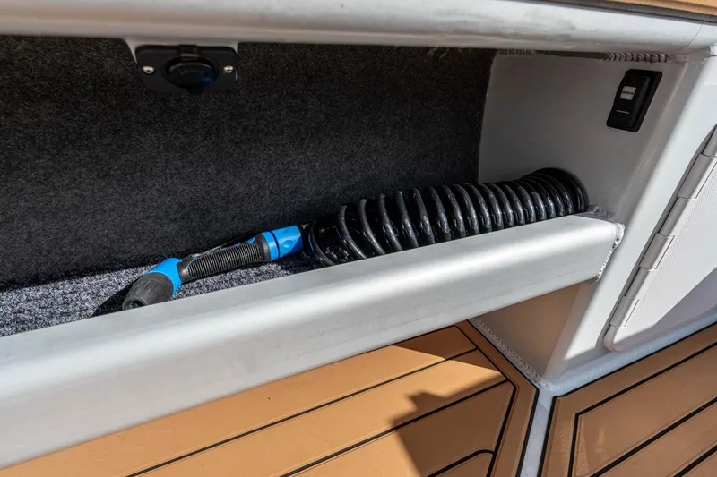 Slide: The Image of Storage compartment in 2025 Makaira Gen 3 36 boat with coiled hose and switch. - 16