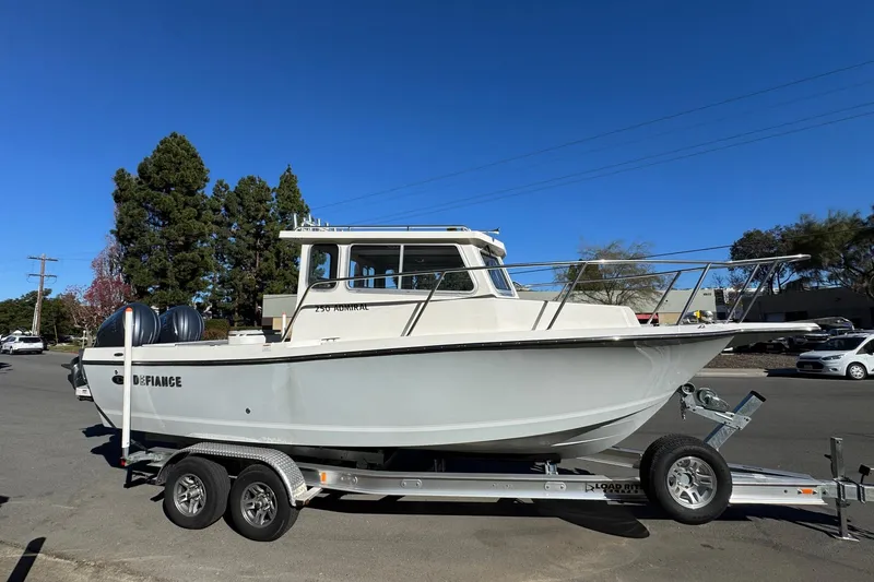Slide: The Image of 2026 Defiance Admiral 250 EX boat on trailer, parked outdoors under clear blue sky. - 16