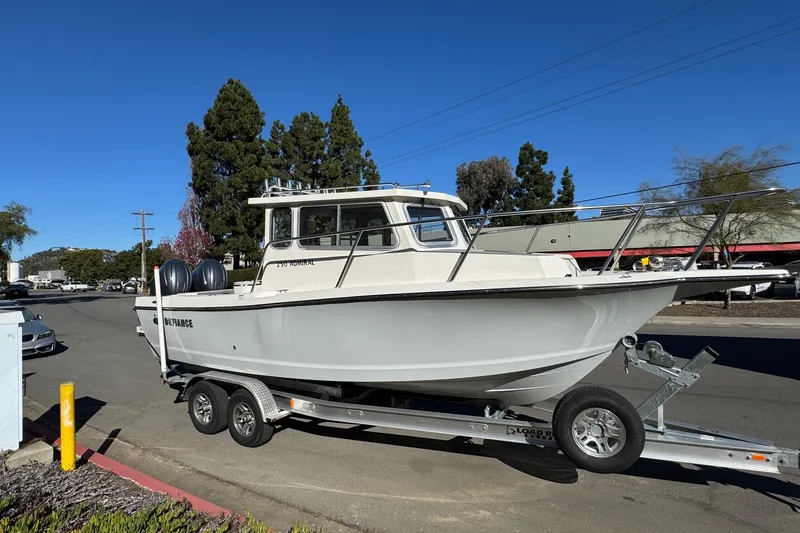 Slide: The Image of 2026 Defiance Admiral 250 EX boat on trailer, parked on street under clear blue sky. - 17