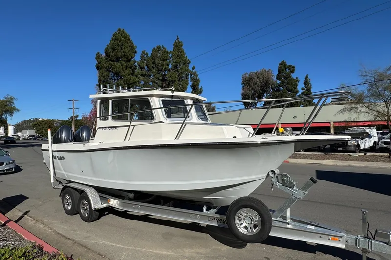Slide: The Image of 2026 Defiance Admiral 250 EX boat on trailer, parked on street under clear blue sky. - 18