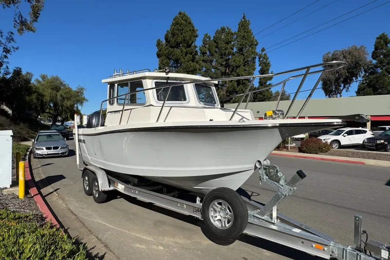 Slide: The Image of 2026 Defiance Admiral 250 EX boat on trailer, parked on street under clear blue sky. - 19