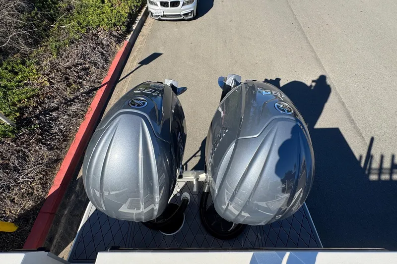 Slide: The Image of Twin outboard motors on a 2026 Defiance Admiral 250 EX boat, parked near a curb. - 26