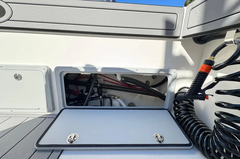 Slide: The Image of Open storage compartment on 2026 Defiance Admiral 250 EX boat, showing interior wiring and hoses. - 43