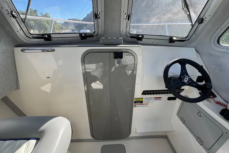 Slide: The Image of Interior of 2026 Defiance Admiral 250 EX boat with steering wheel and windows. - 98