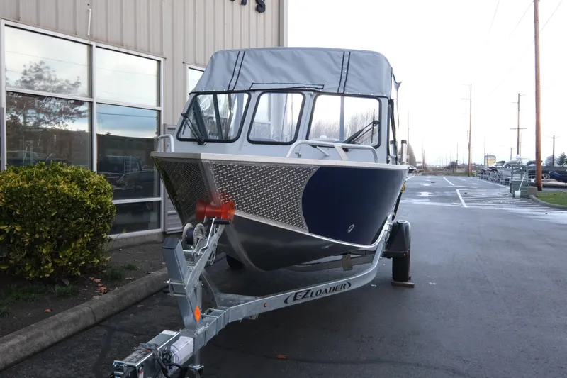Slide: The Image of 2026 Hewescraft 180 Sportsman boat on trailer, parked outside a building. - 3