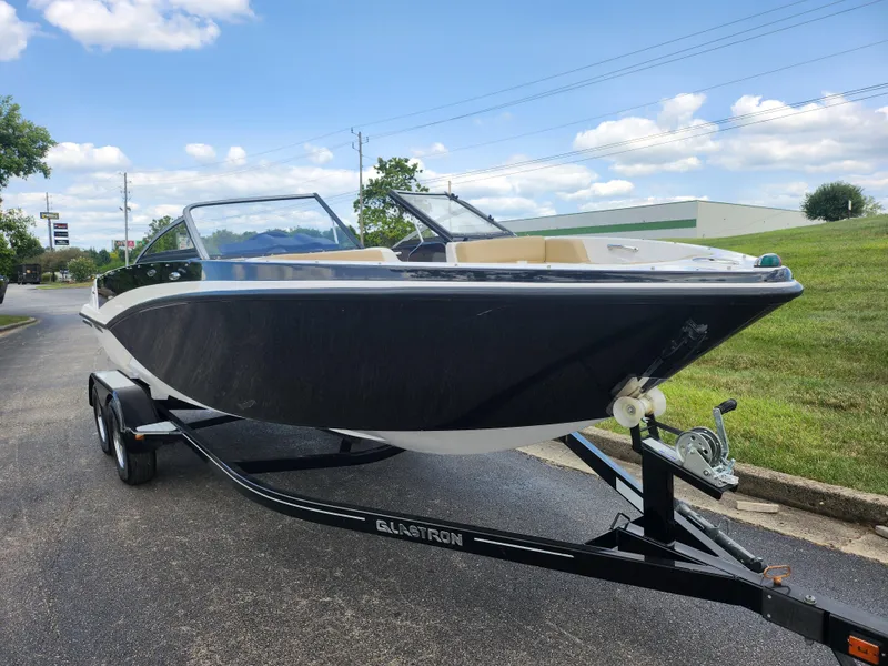 Slide: The Image of 2016 Glastron GT 205 boat on trailer, parked outdoors under a blue sky. - 6