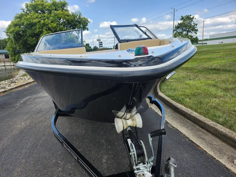Slide: The Image of 2016 Glastron GT 205 boat on trailer, parked on asphalt near grass and trees. - 7