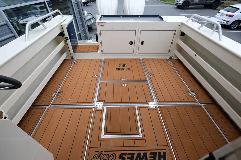 Slide: The Image of 2025 Hewescraft 290 Adventure boat deck with wood finish and storage compartments. - 8