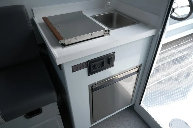 Slide: The Image of 2025 Hewescraft 270 Alaskan interior with compact kitchen setup, featuring sink and stove. - 18