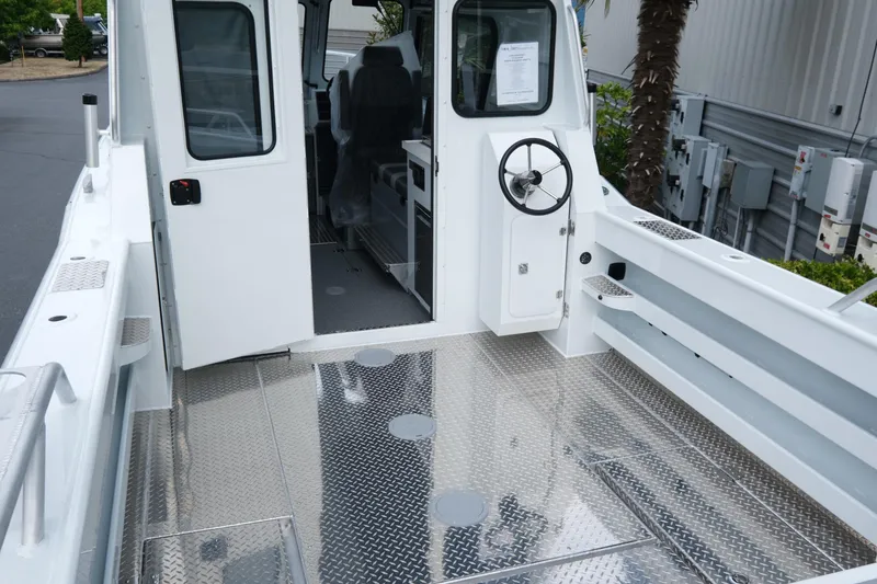 Slide: The Image of 2025 Hewescraft 270 Alaskan boat interior with open cabin door and steering wheel. - 8