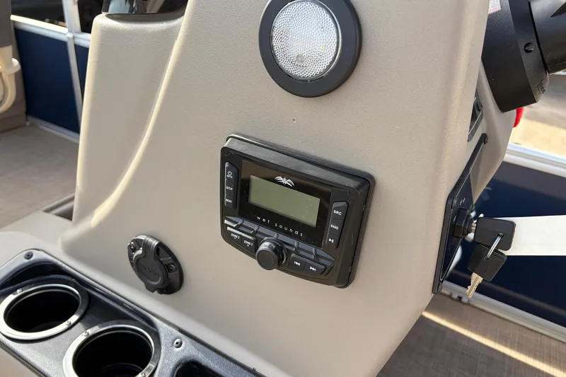 Slide: The Image of Control panel of 2025 Sun Tracker Bass Buggy 18 DLX with audio system and cup holders. - 25