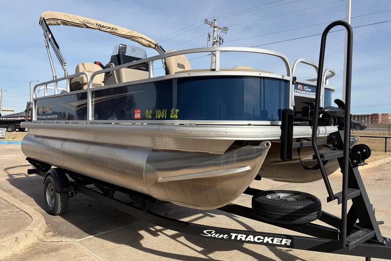 Slide: The Image of 2025 Sun Tracker Bass Buggy 18 DLX pontoon boat on trailer, outdoor setting. - 3