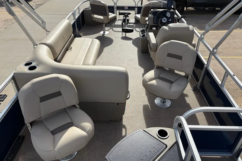 Slide: The Image of 2025 Sun Tracker Bass Buggy 18 DLX pontoon boat interior with beige seating and steering console. - 9