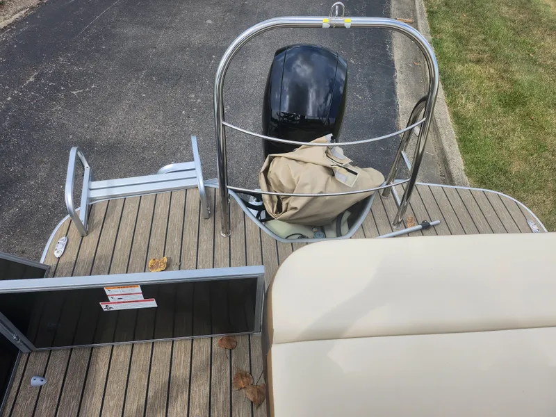 Slide: The Image of 2022 Lowe SS 210 CL pontoon boat with motor and seating, docked on pavement. - 14