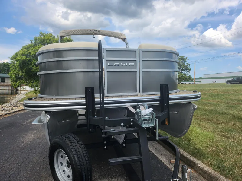 Slide: The Image of 2022 Lowe SS 210 CL pontoon boat on trailer, parked outdoors under a cloudy sky. - 6