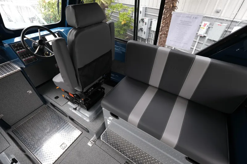 Slide: The Image of Interior of 2025 Hewescraft 270 Alaskan boat with steering and seating area. - 12