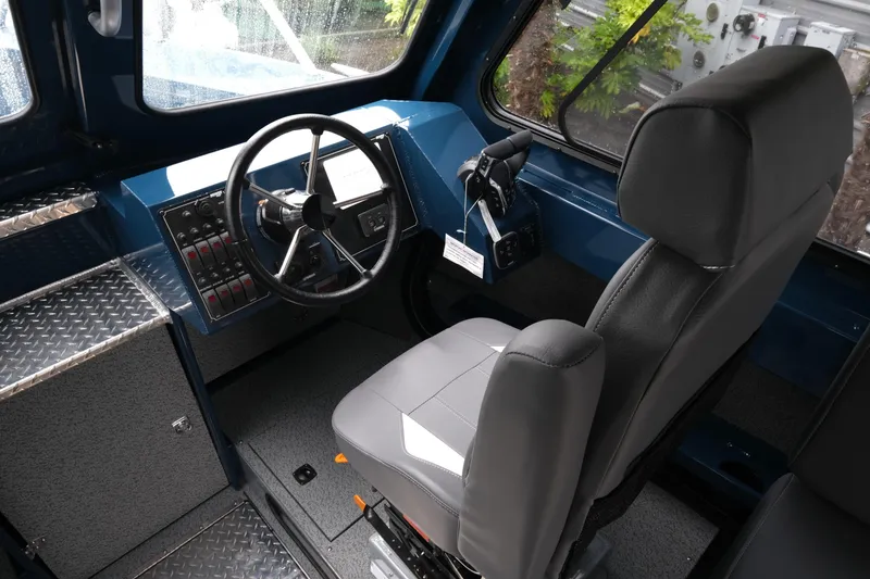 Slide: The Image of Interior of 2025 Hewescraft 270 Alaskan boat, featuring steering wheel and captain's chair. - 13