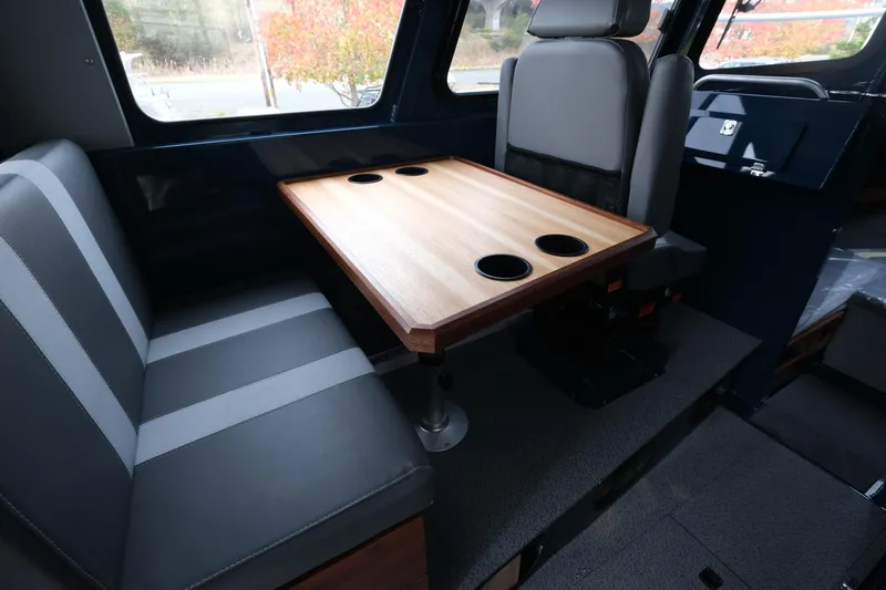 Slide: The Image of Interior of 2026 Hewescraft 250 Pacific Explorer with seating and table featuring cup holders. - 11