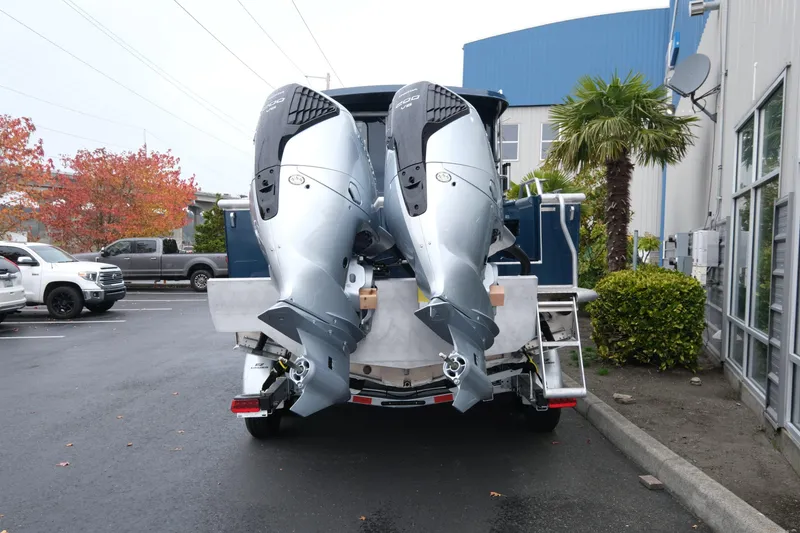 Slide: The Image of 2026 Hewescraft 250 Pacific Explorer with dual outboard motors in a parking lot. - 5