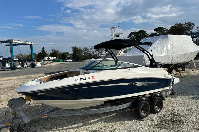 Slide: The Image of 2015 Sea Ray 220 Sundeck Outboard boat on trailer in marina setting. - 0