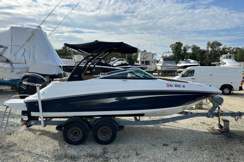 Slide: The Image of 2015 Sea Ray 220 Sundeck Outboard boat on trailer, parked in marina. - 15