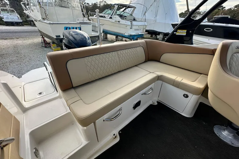 Slide: The Image of 2015 Sea Ray 220 Sundeck Outboard interior with beige seating and storage compartments. - 20