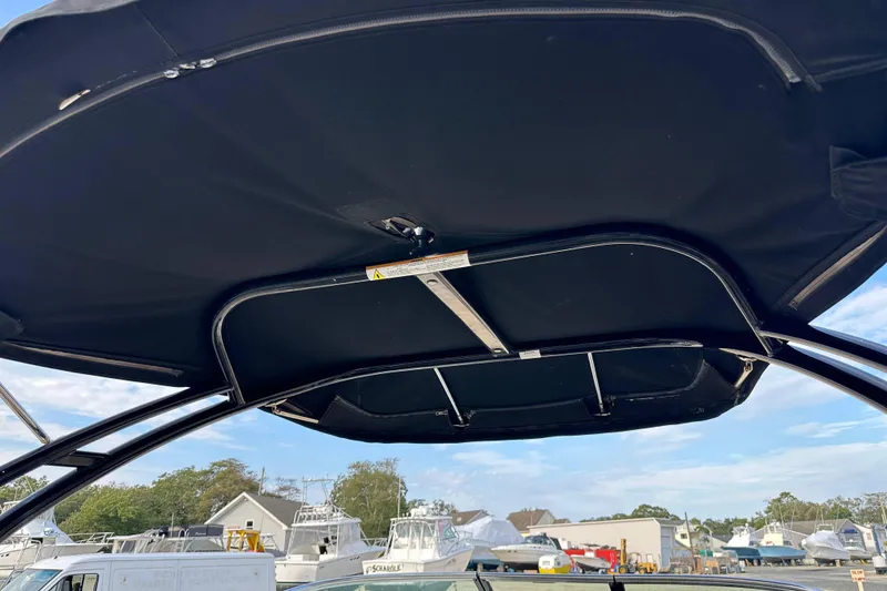 Slide: The Image of 2015 Sea Ray 220 Sundeck Outboard boat canopy, marina background, clear sky. - 26