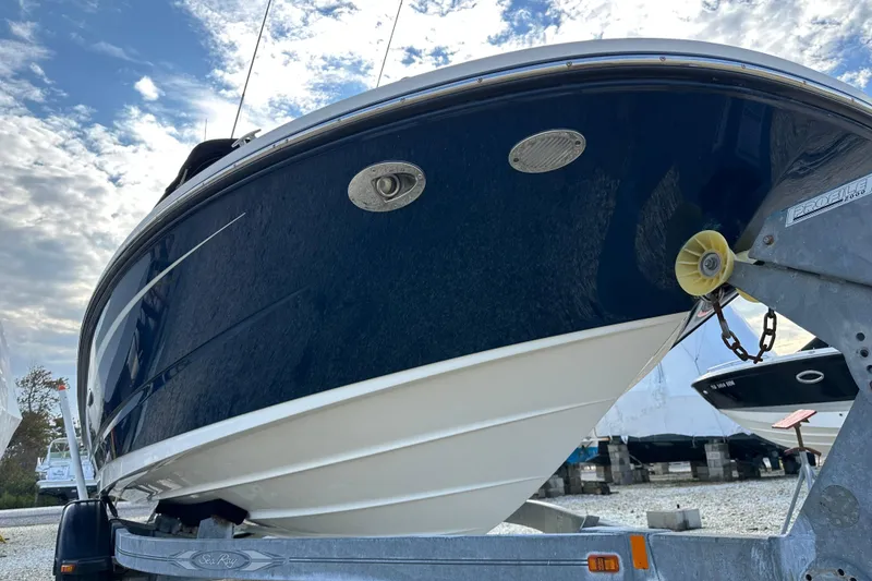 Slide: The Image of 2015 Sea Ray 220 Sundeck Outboard on trailer under a partly cloudy sky. - 28