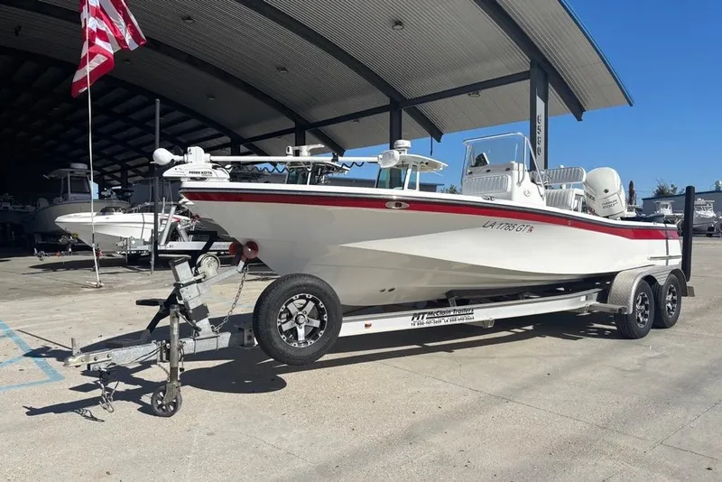 Slide: The Image of 2013 BlackJack 224 boat on trailer, parked under a canopy with American flag. - 1