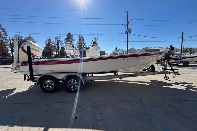 Slide: The Image of 2013 BlackJack 224 boat on trailer, parked outdoors under clear blue sky. - 4