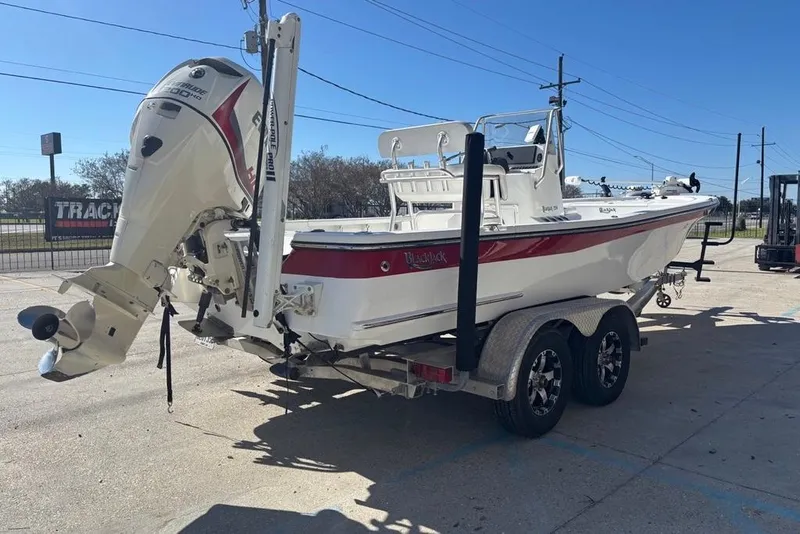 Slide: The Image of 2013 BlackJack 224 boat on trailer with Evinrude outboard motor, parked outdoors. - 5