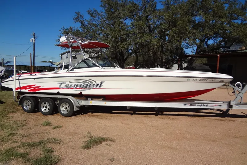 The Image of 2003 Ski Centurion Tsunami boat on trailer, white with red accents, parked outdoors. - 0