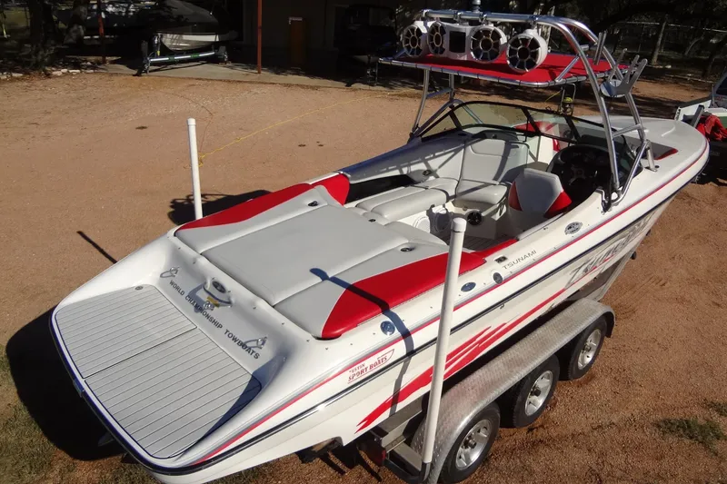 Slide: The Image of 2003 Ski Centurion Tsunami boat with red and white design on a trailer. - 2
