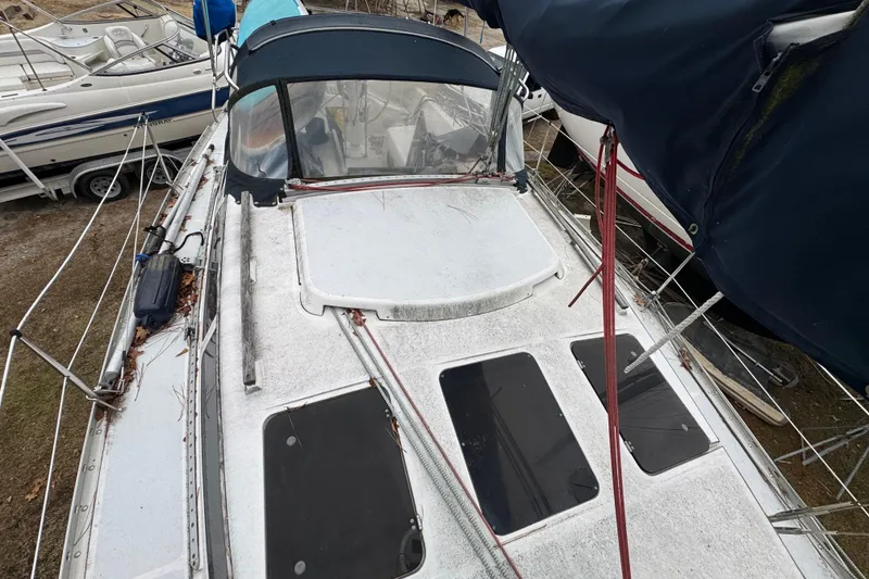 Slide: The Image of 1992 Hunter 33.5 sailboat deck with canopy and hatches, docked alongside other boats. - 12