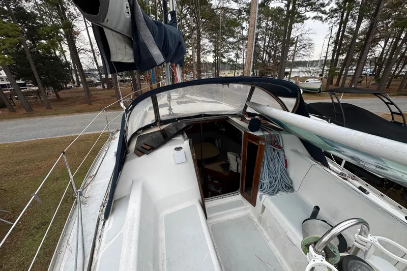 Slide: The Image of 1992 Hunter 33.5 sailboat cockpit with ropes and steering wheel, docked near trees. - 17