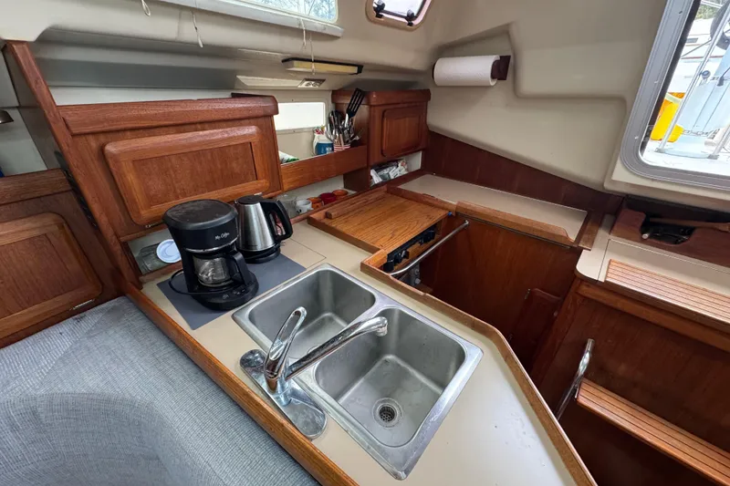 Slide: The Image of Interior of a 1992 Hunter 33.5 sailboat kitchen with sink, coffee maker, and wooden cabinetry. - 45