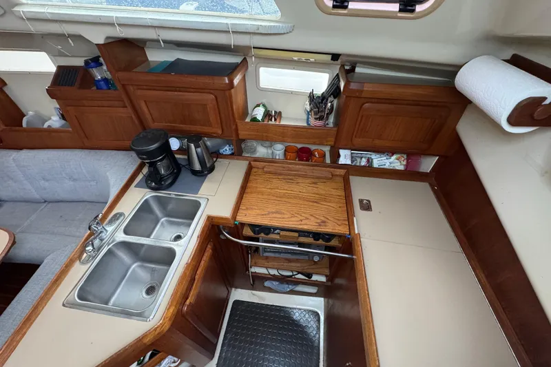Slide: The Image of Interior of a 1992 Hunter 33.5 sailboat kitchen with sink, coffee maker, and wooden cabinets. - 47