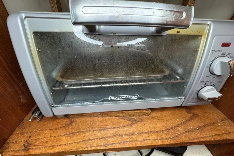Slide: The Image of A Black & Decker toaster oven on a wooden shelf, showing signs of use. - 50